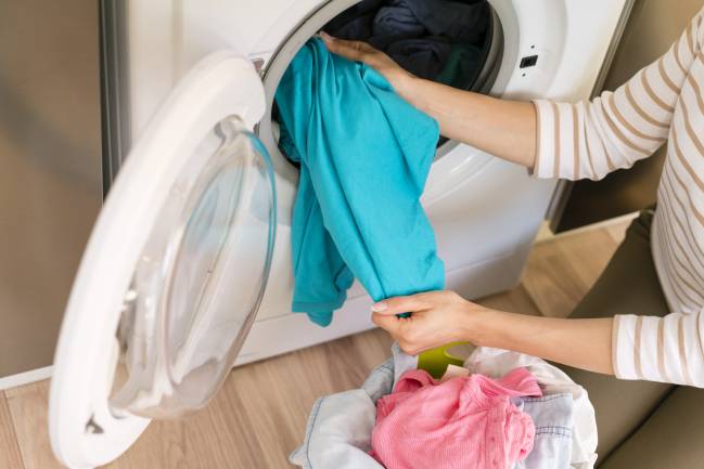 Persona recogiendo ropa de la lavadora. 